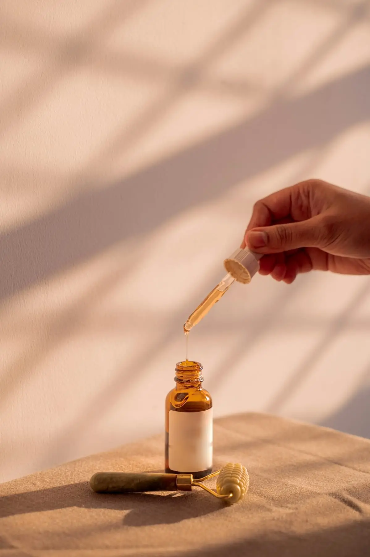 Illustratives Stockfoto: Pipette über einem Serumfläschchen, daneben ein Gesichtsroller